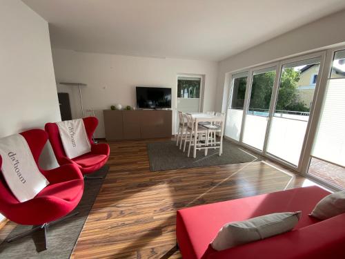 a living room with two red chairs and a table at „1. SALZBURG work & sleep luxury apartment“ für arbeiten & wohnen ! in Salzburg