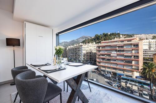 une salle à manger avec une table blanche et une grande fenêtre dans l'établissement Le Cap Riviera, à Menton