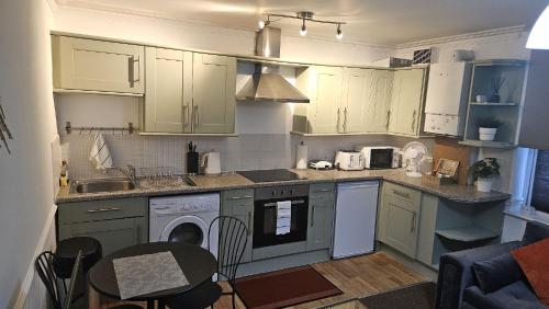 una cucina con armadi bianchi, tavolo e sedie di Nariken Apartments a Bristol