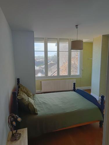a bed in a room with two windows at Appartement au charme authentique in Mirecourt