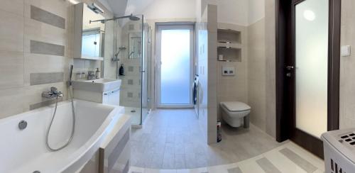 La salle de bains est pourvue d'une baignoire, d'un lavabo et de toilettes. dans l'établissement Lux Apartmán Centrum, à Topoľčany