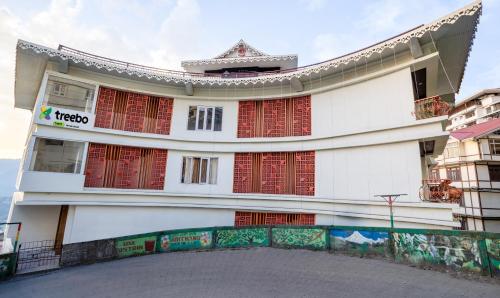 ein großes weißes Gebäude mit roten Fenstern in der Unterkunft Itsy By Treebo - Meraki Grand in Gangtok