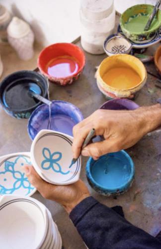 a person painting a bowl with paint on it at The View Agadir in Agadir