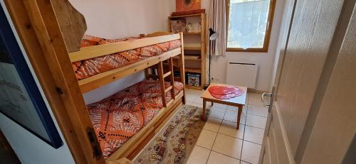 Kleines Zimmer mit 2 Etagenbetten und einem Tisch in der Unterkunft Le Chamois 2 in Laye