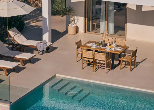 a patio with a table and chairs next to a pool at Thelxi's Suite II - Brand New Seaview Suite! in Volimes