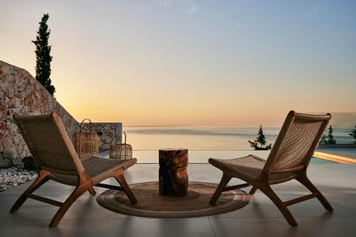 two chairs and a table on a patio with the ocean at Thelxi's Suite II - Brand New Seaview Suite! in Volimes