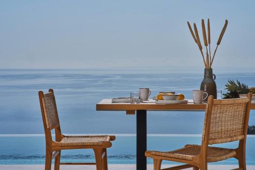 a table with two chairs and a table with food on it at Thelxi's Suite II - Brand New Seaview Suite! in Volimes