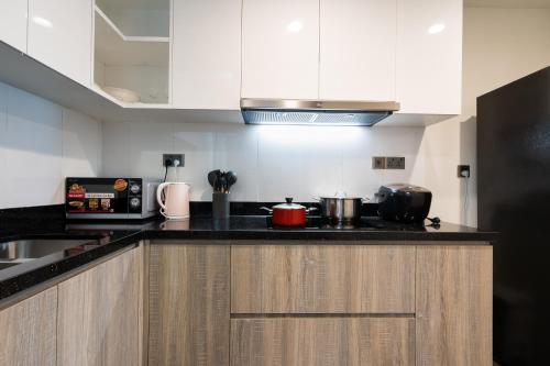 a kitchen with white cabinets and a black counter top at DingD0ng Home FelizEnVista 5-star facilities in Ho Chi Minh City