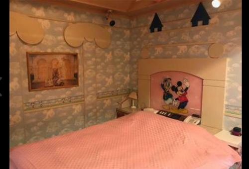 Schlafzimmer mit einem Bett mit rosa Tagesdecke in der Unterkunft 綾部アイネ in Ayabe