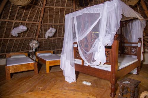 a room with two beds and a canopy at Bottle Cottage in Shimoni