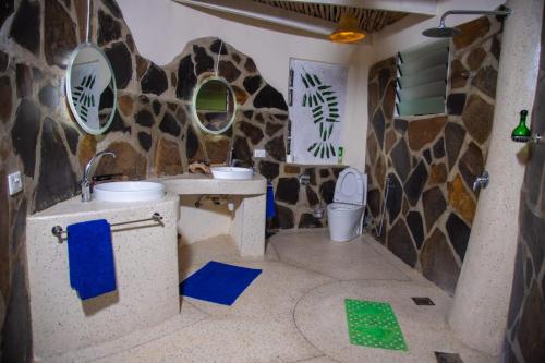 a bathroom with a toilet and a stone wall at Bottle Cottage in Shimoni
