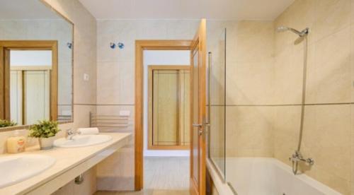 La Guirra的住宿－CASA LOTTIE，浴室配有2个盥洗盆、浴缸和淋浴。