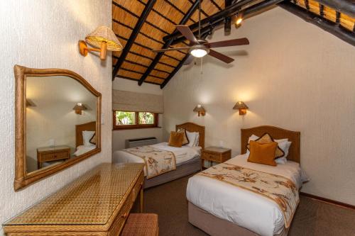 een slaapkamer met 2 bedden en een spiegel bij Kruger Park Lodge Unit No. 216 in Hazyview