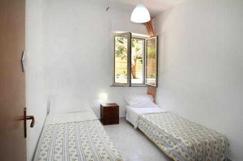 1 dormitorio con 2 camas y ventana en Appartamento con Cortile Privato, en Santo Stefano di Camastra