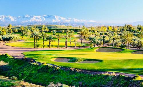 een golfbaan met palmbomen en bergen op de achtergrond bij Villa Marrakech in Marrakesh
