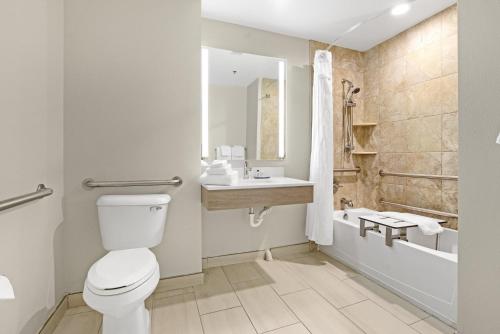 a bathroom with a toilet and a sink and a tub at Holiday Inn Express - Gulfport Beach by IHG in Gulfport