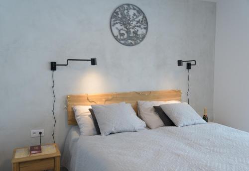 uma cama com almofadas brancas e um relógio na parede em Apartmány StudenOFF em Rokytnice nad Jizerou
