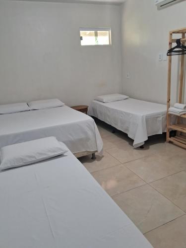 um quarto com três camas e uma janela em Suítes flor de Mandacaru em Piranhas