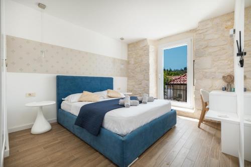 a bedroom with a blue bed and a window at Villa Komelo in Škrip