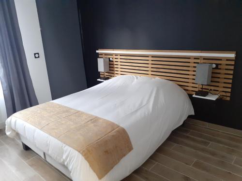 a bedroom with a large white bed with a wooden headboard at Lens Louvre 2 in Lens