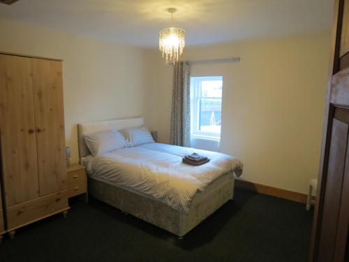 1 dormitorio con 1 cama con lámpara de araña y ventana en The Heritage Guest House en Montrose