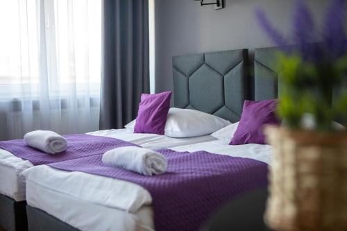a bed with purple and white sheets and pillows at WRZOS resort & wellness in Węgierska Górka