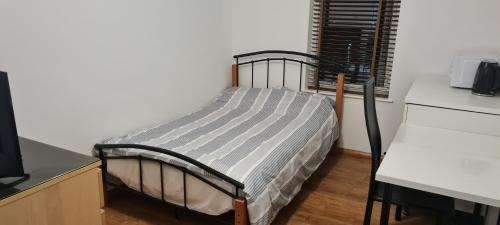 Luton, LU3 Double Ensuite room في لوتون: سرير في غرفة بجانب مكتب وبه جهاز كمبيوتر