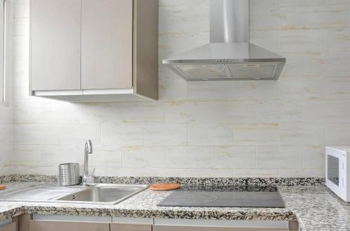 cocina blanca con fregadero y microondas en Apartamento amplio, en Sevilla