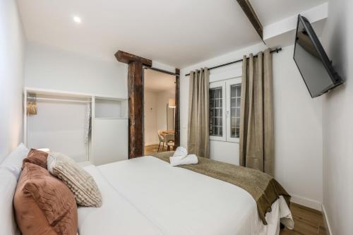 sypialnia z białym łóżkiem i telewizorem w obiekcie Encantador apartamento Plaza del Callao w Madrycie
