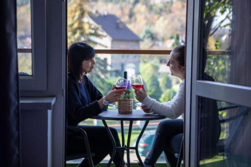 two women sitting at a table with glasses of wine at WRZOS resort & wellness in Węgierska Górka