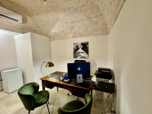 um escritório com uma secretária, um computador e cadeiras verdes em Trulli Contento - Rooms & Apartments em Alberobello