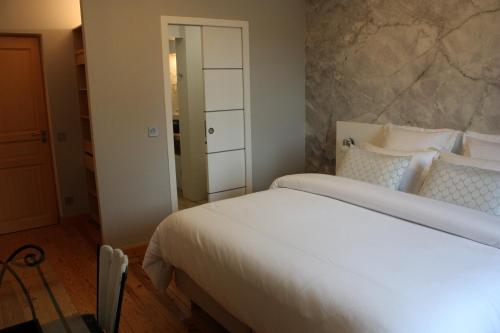 a bedroom with a large white bed and a mirror at L'Escale de Beauregard in Coublevie