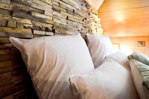a bed with white pillows against a brick wall at Les Jardins d'Epicure in Bray-et-Lû