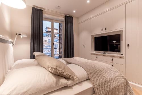 a white bedroom with a large bed with a television at weivz SPO Reetdachhaus weivz SPO in Sankt Peter-Ording