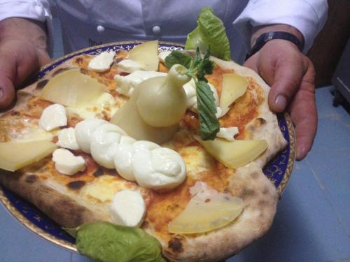 a person holding a plate of pizza with vegetables on it at Antica Conca D'oro in Ogliastro Cilento