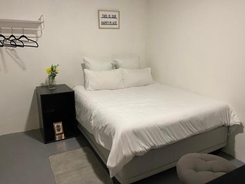 Schlafzimmer mit einem Bett mit weißer Bettwäsche und einem Tisch in der Unterkunft Peaceful Suburban Utopia in Sandton