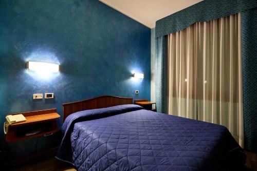 a bedroom with a purple bed and a blue wall at HOTEL PARADISO in Altedo