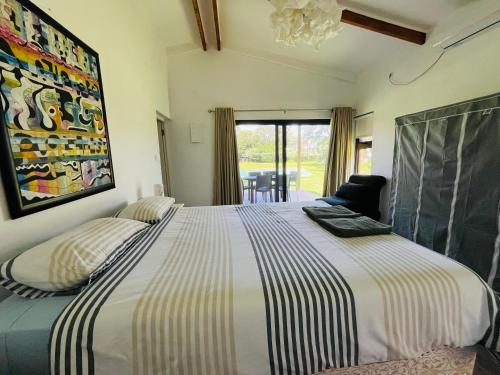 a bedroom with a large bed with striped sheets at Twin House #2 in Ponta do Ouro