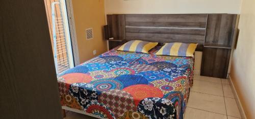 1 dormitorio con 1 cama con un edredón colorido en Vacances paisibles en Saint-Paul