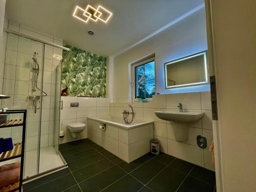 a bathroom with a tub and a sink and a toilet at Ferienwohnung im Grünen in Oranienburg