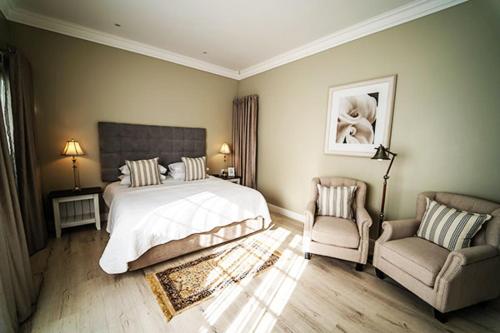 a bedroom with a bed and a couch and a chair at AnnVilla Guesthouse in Klerksdorp