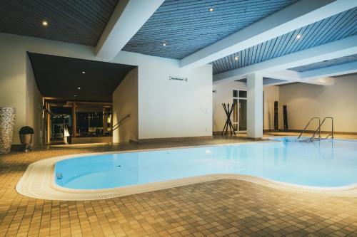 a large swimming pool in a building with a large tub at Hotel Lauterbad in Freudenstadt