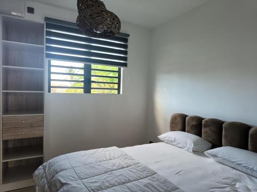 - une chambre avec un lit et une fenêtre avec des stores dans l'établissement Villa June, à Triolet