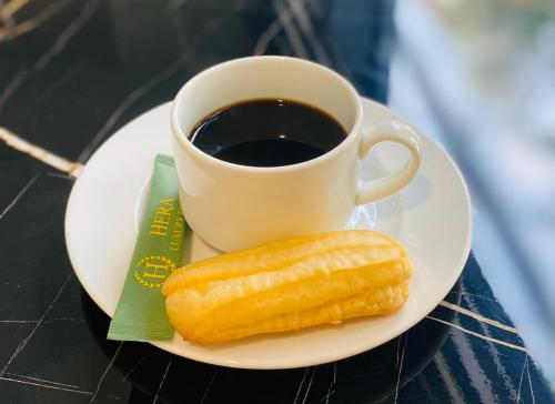 a plate with a pastry and a cup of coffee at Hera Luxury Hotel in Ho Chi Minh City