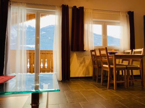 a dining room with a table and chairs and windows at Appartement in Uttendorf