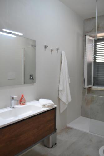 a white bathroom with a sink and a shower at L' Isola di Bacco in Porto Cesareo