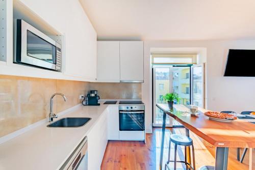 a kitchen with white cabinets and a wooden counter top at Guest Inn 2 Boutique House in Lisbon