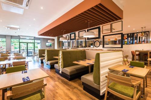 a restaurant with wooden tables and green chairs at Holiday Inn Lancaster by IHG in Lancaster