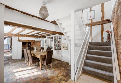 a dining room with a table and chairs and a staircase at Historical and Quirky Home in Braintree