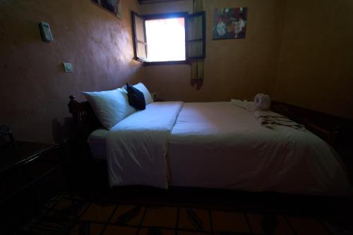 a bedroom with a white bed with a window at Chez Brahim vue panoramique in Aït Ben Haddou